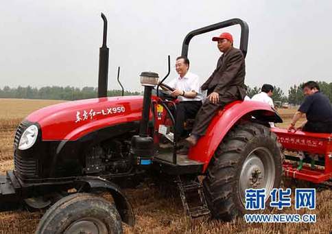 6月10日，在河南省許昌縣陳曹鄉后孫汪村高產小麥示范區，中共中央政治局常委、國務院總理溫家寶登上一臺“東方紅”牌拖拉機的駕駛室，在司機的指導下掛擋、加油，緊握方向盤，穩穩地駕駛著，在剛剛收割的麥地里深耕、施肥，種下秋玉米。新華社記者龐興雷攝 