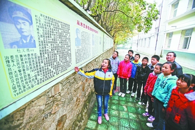 上圖：學校文化墻前，小講解員講述開國將軍杜義德的故事。記者何曉剛 攝