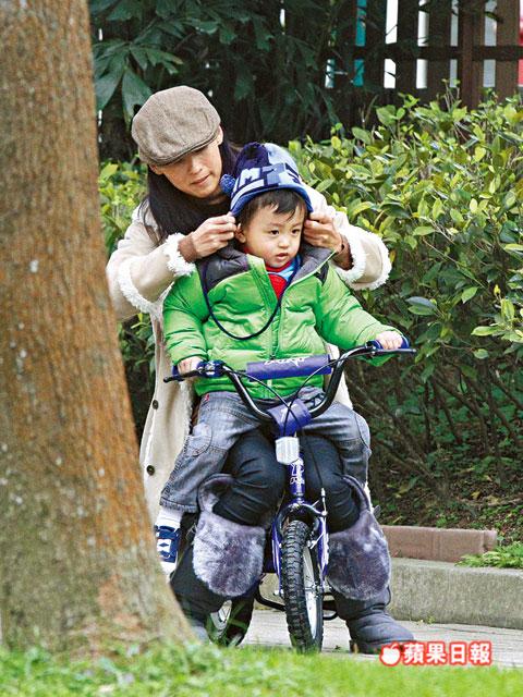 張柏芝抱quintus坐踩單車，又細心幫他整理冷帽